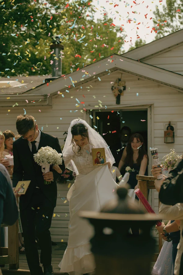 A bride and groom leaving their ceremony under a shower of colourful confetti